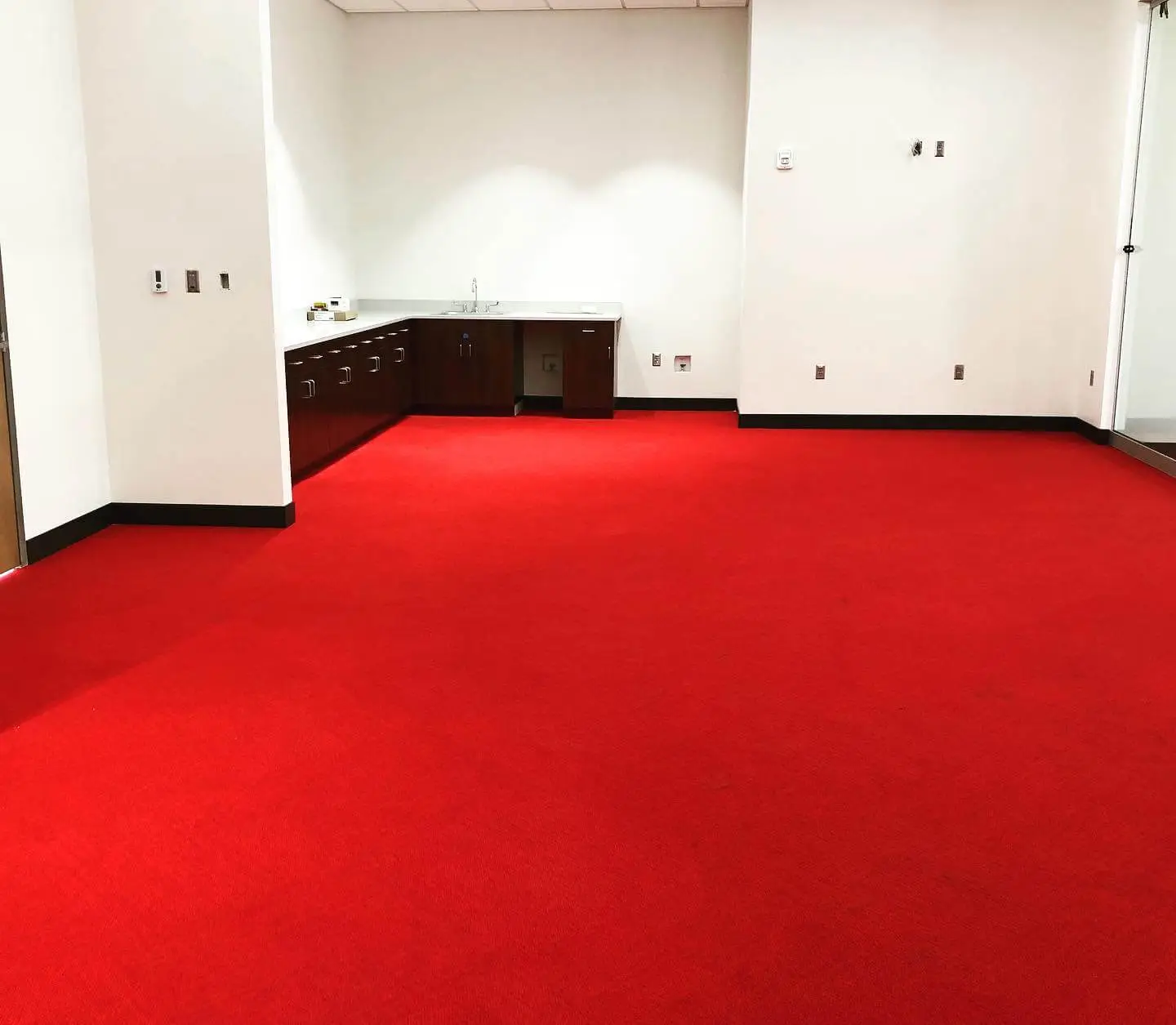 Red carpet newly installed in an office meeting room with a sink and white walls